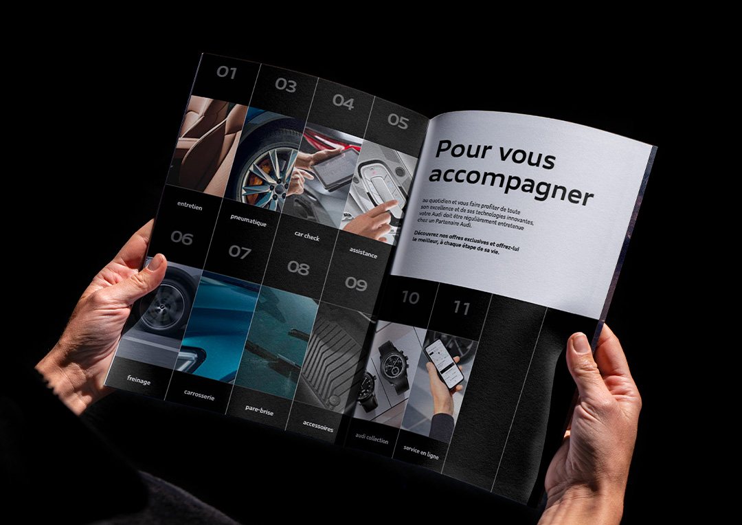 An open Audi service brochure held in two hands